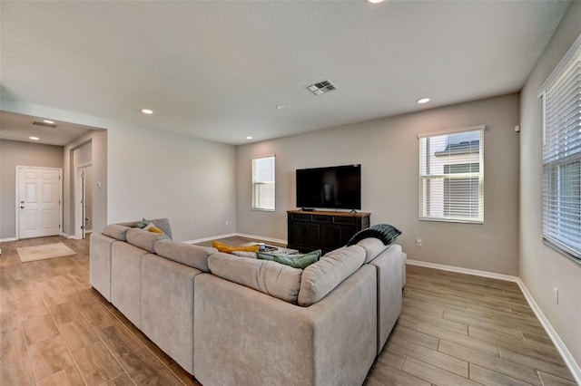 living area with visible vents, plenty of natural light, baseboards, and light wood-type flooring
