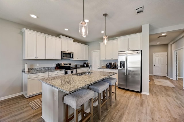 kitchen with a kitchen breakfast bar, a sink, light wood-style floors, visible vents, and appliances with stainless steel finishes