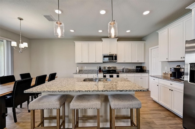kitchen with a kitchen breakfast bar, a sink, stainless steel appliances, and visible vents