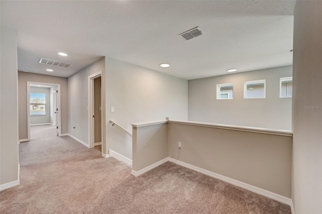 corridor featuring carpet floors, an upstairs landing, baseboards, and visible vents