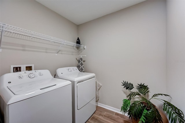 clothes washing area with wood finish floors, baseboards, washer and dryer, and laundry area