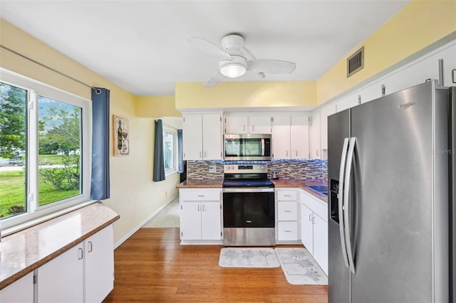 kitchen featuring visible vents, appliances with stainless steel finishes, decorative backsplash, and white cabinetry