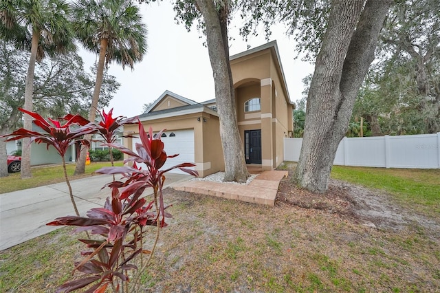 view of front of home with stucco siding, fence, concrete driveway, a front yard, and a garage