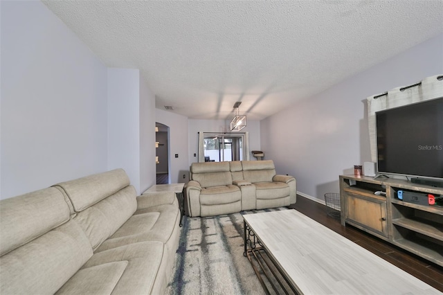 living room featuring visible vents, arched walkways, a textured ceiling, and dark wood finished floors