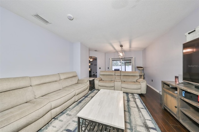 living room with visible vents, baseboards, a textured ceiling, and dark wood-style flooring