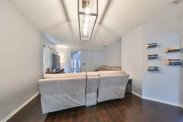 living area featuring dark wood-style floors, visible vents, a textured ceiling, and baseboards