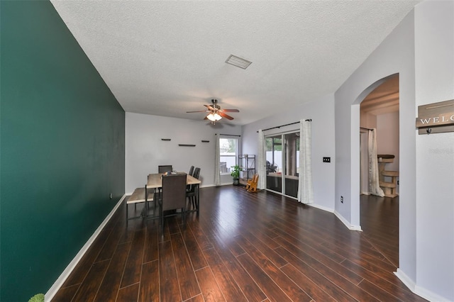 unfurnished office featuring visible vents, baseboards, wood finished floors, arched walkways, and a textured ceiling