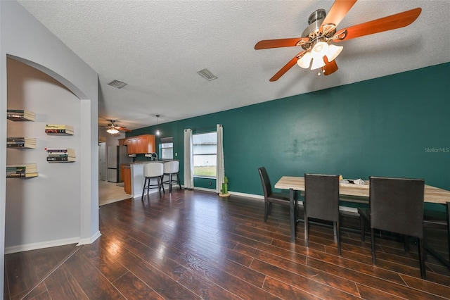 dining room with a textured ceiling, wood finished floors, visible vents, and baseboards