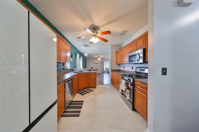 kitchen featuring visible vents, a peninsula, appliances with stainless steel finishes, a textured ceiling, and dark countertops