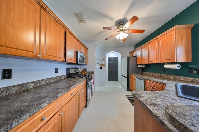 kitchen featuring arched walkways, visible vents, brown cabinets, and stainless steel appliances