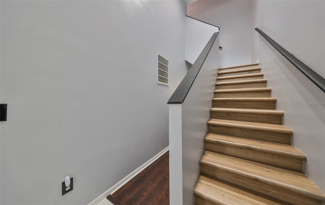 stairs with visible vents, baseboards, and wood finished floors