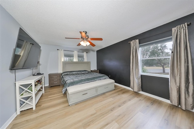 bedroom featuring multiple windows, light wood-style floors, and a textured ceiling