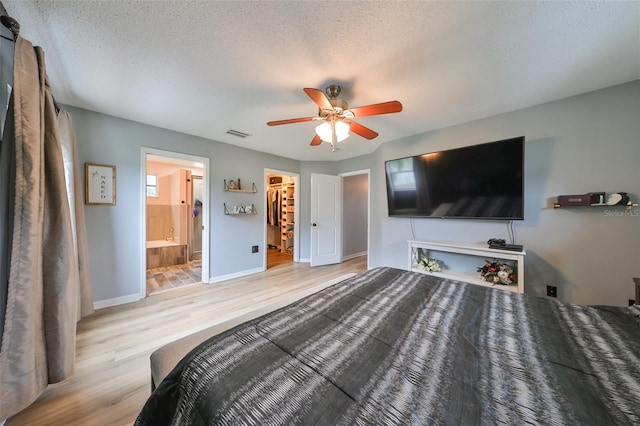 bedroom with a walk in closet, wood finished floors, visible vents, and a textured ceiling