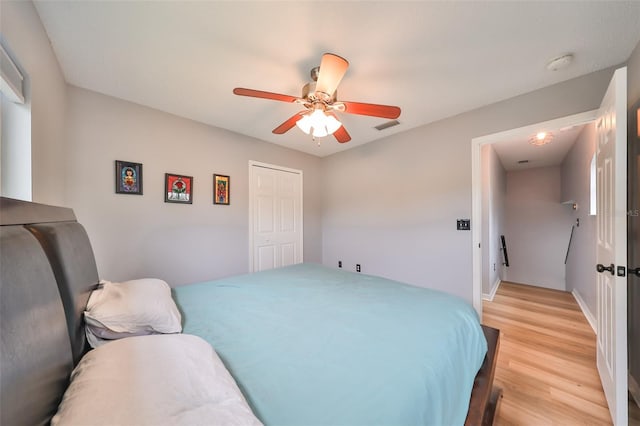 bedroom featuring visible vents, baseboards, light wood-type flooring, a closet, and a ceiling fan