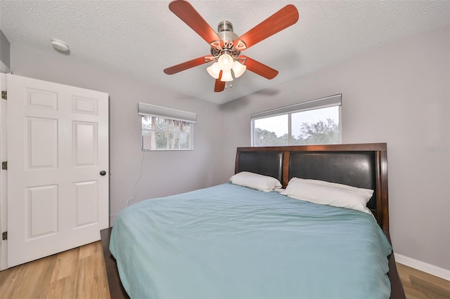 bedroom featuring baseboards, a textured ceiling, wood finished floors, and a ceiling fan