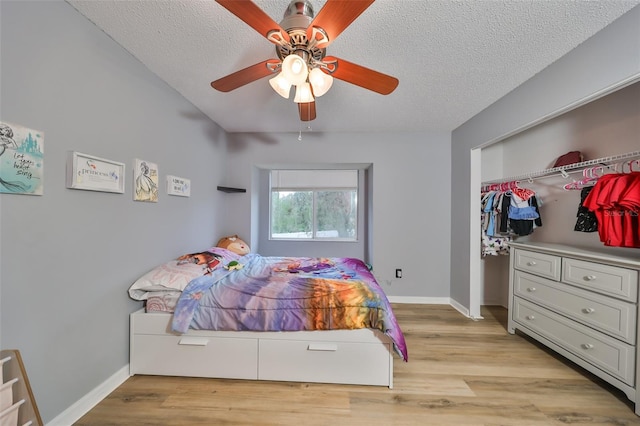 bedroom featuring baseboards, light wood-style floors, and a textured ceiling