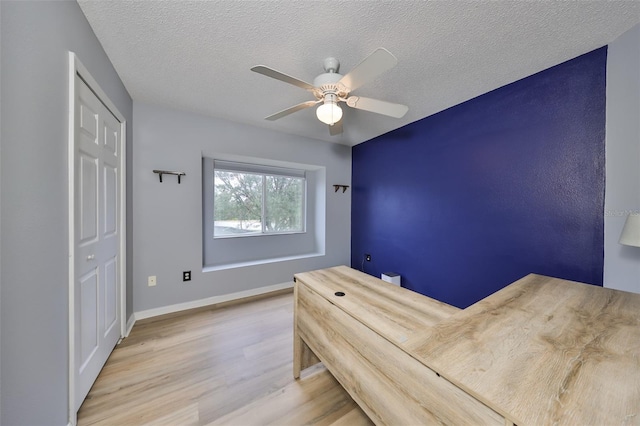 unfurnished bedroom with baseboards, a textured ceiling, a ceiling fan, and wood finished floors