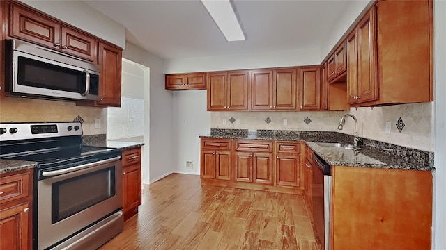 kitchen featuring light wood-style floors, tasteful backsplash, appliances with stainless steel finishes, and a sink