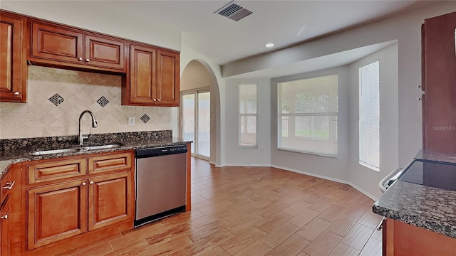 kitchen with visible vents, decorative backsplash, stainless steel dishwasher, arched walkways, and a sink