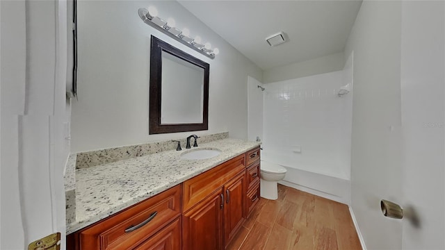 bathroom with bathing tub / shower combination, toilet, wood finished floors, and vanity