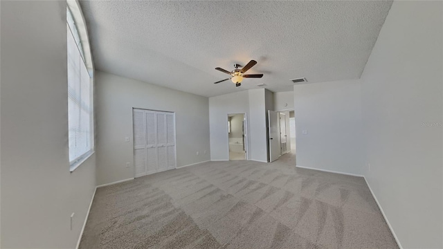 unfurnished bedroom with baseboards, visible vents, a closet, a textured ceiling, and carpet flooring