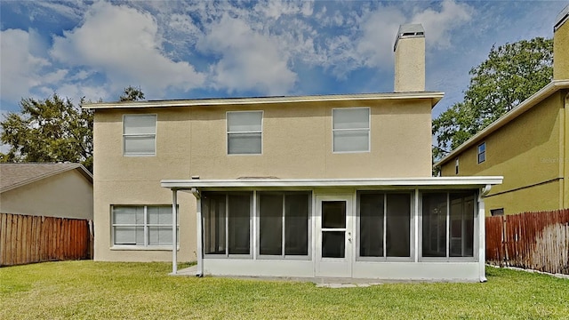 back of property featuring stucco siding, a lawn, fence, and a sunroom