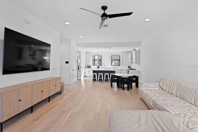 living room featuring recessed lighting, a ceiling fan, visible vents, and light wood-type flooring