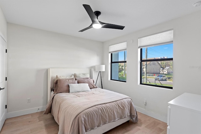 bedroom featuring light wood-style flooring, baseboards, and ceiling fan