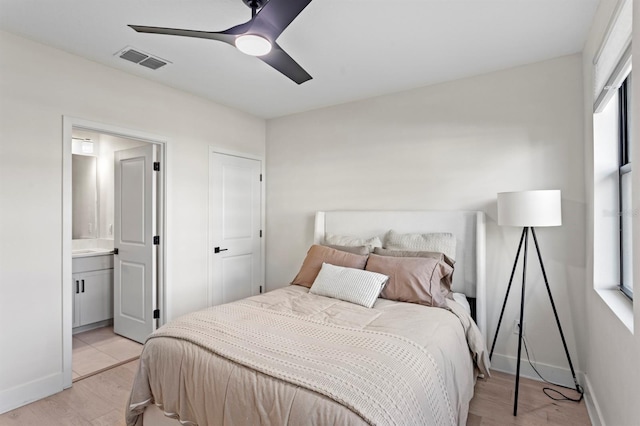 bedroom featuring visible vents, baseboards, connected bathroom, and light wood finished floors