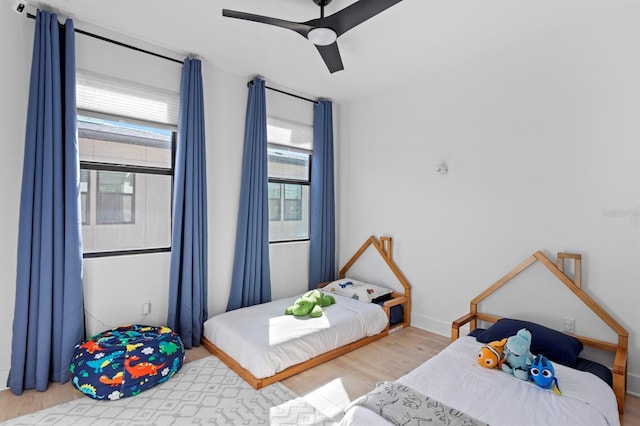 bedroom with a ceiling fan, wood finished floors, and baseboards