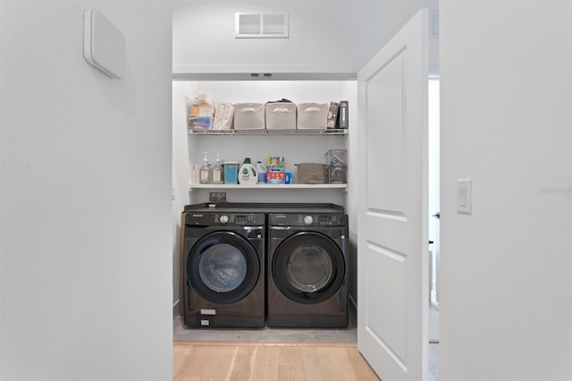 clothes washing area featuring visible vents, a dry bar, laundry area, wood finished floors, and washer and dryer