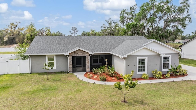 ranch-style house with stone siding, roof with shingles, a front yard, and a gate