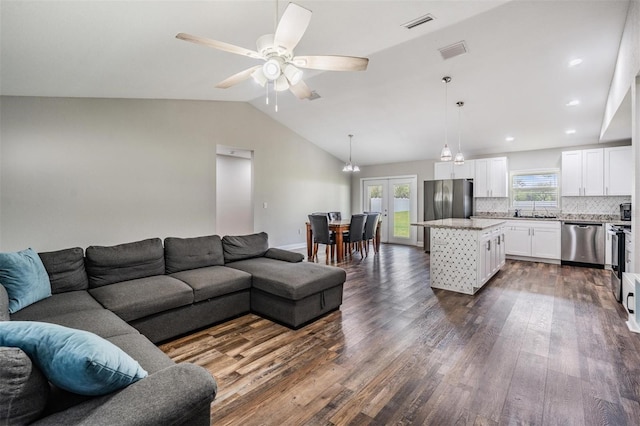 living room with a ceiling fan, lofted ceiling, visible vents, and dark wood-style flooring