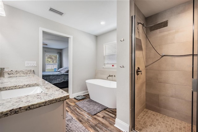 ensuite bathroom featuring ensuite bath, wood finished floors, visible vents, and a stall shower