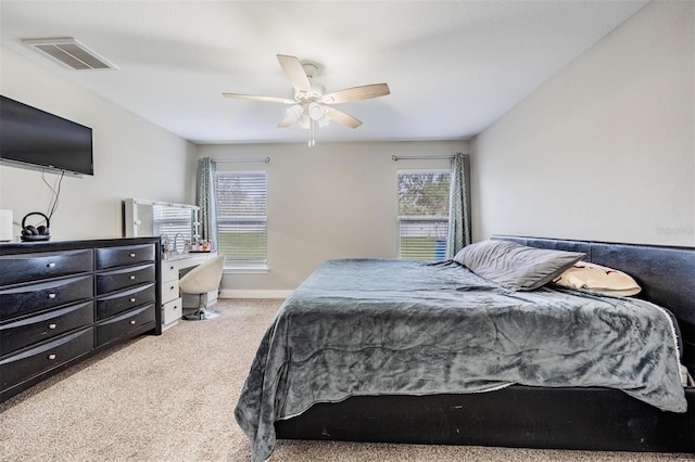 carpeted bedroom with visible vents, multiple windows, baseboards, and ceiling fan