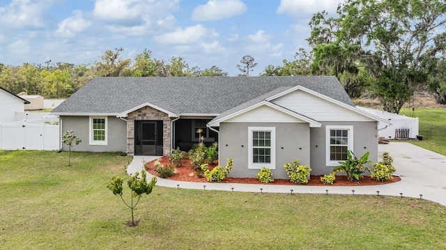 single story home with a gate, stone siding, fence, roof with shingles, and a front yard