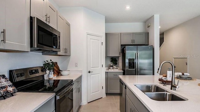 kitchen featuring a sink, appliances with stainless steel finishes, gray cabinets, and light countertops