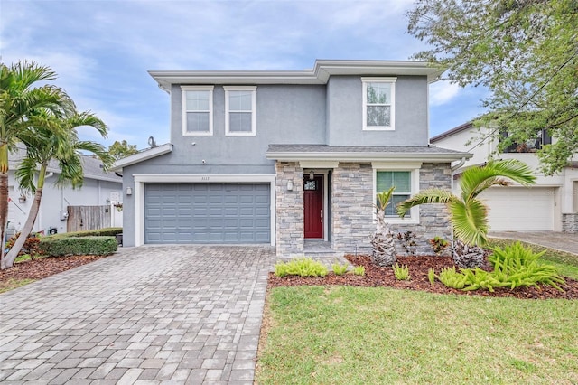 traditional-style house featuring stone siding, stucco siding, decorative driveway, and a garage