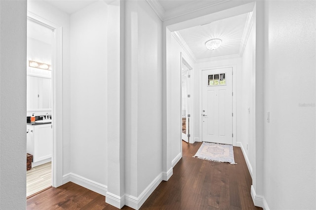 hallway with dark wood finished floors, crown molding, baseboards, and a sink