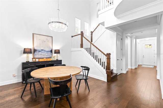 dining room with a towering ceiling, dark wood finished floors, stairs, and crown molding