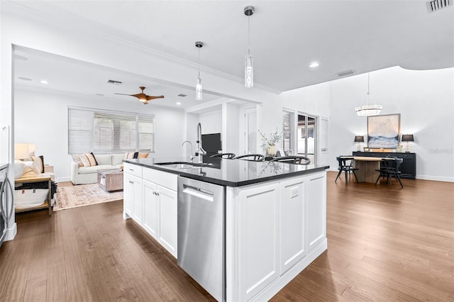 kitchen with dark countertops, visible vents, dark wood-type flooring, stainless steel dishwasher, and a sink