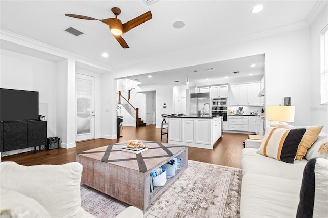 living room with dark wood-style floors, visible vents, stairway, and ornamental molding