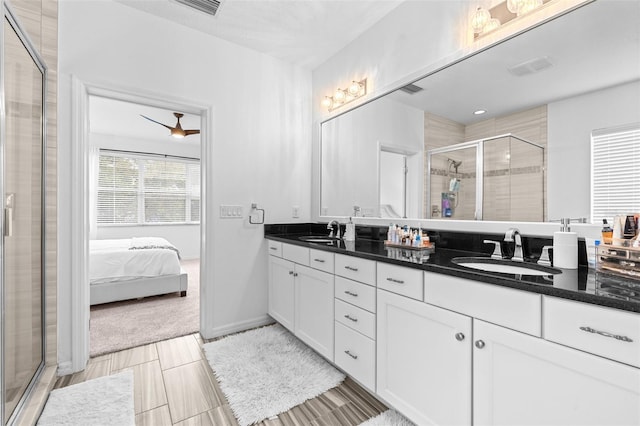 ensuite bathroom with a sink, baseboards, a stall shower, and double vanity