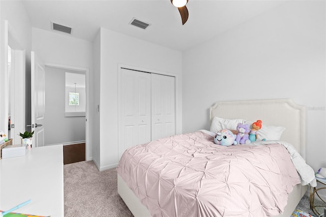 bedroom with a closet, visible vents, light colored carpet, and ceiling fan