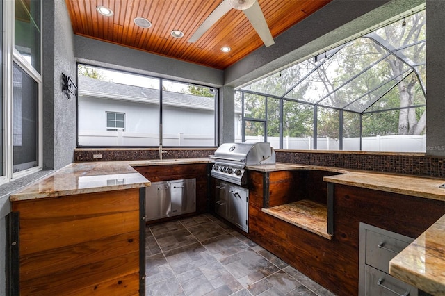 view of patio / terrace featuring fence, a lanai, exterior kitchen, area for grilling, and a ceiling fan