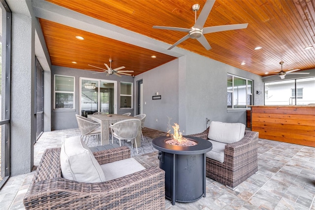 view of patio with an outdoor living space with a fire pit, outdoor dining space, and a ceiling fan