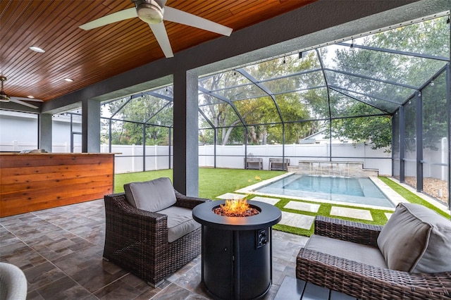 view of patio featuring a fenced in pool, a fenced backyard, ceiling fan, a fire pit, and a lanai