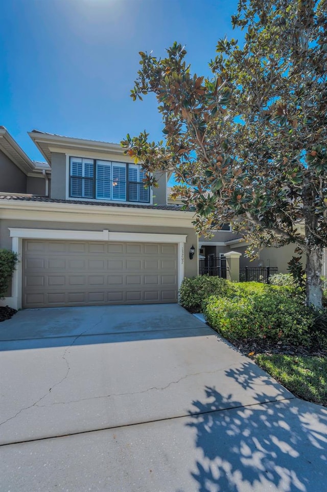 view of front of house featuring stucco siding, an attached garage, driveway, and fence