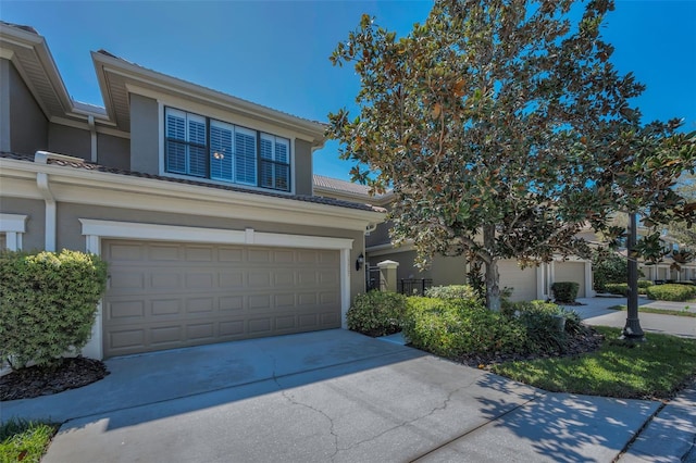 view of front of home with a tile roof, concrete driveway, a garage, and stucco siding