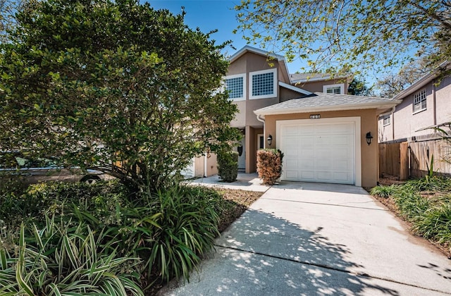 view of front of property featuring stucco siding, fence, roof with shingles, concrete driveway, and an attached garage